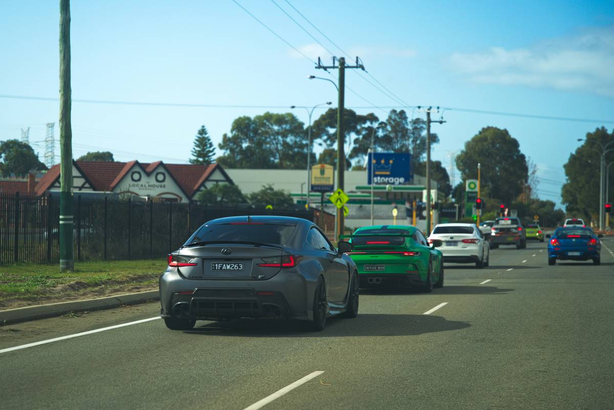 Multiple cars driving on a road under a clear sky.